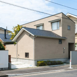 高田のコートハウス　外観　煙突のある西棟がLDKで手前の東棟が和室　コの字型の平面構成